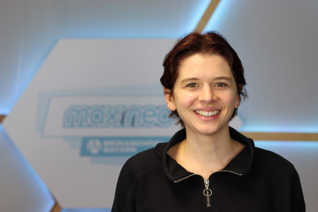 Das Foto zeigt Barbara Müller vor dem max neo Logo.