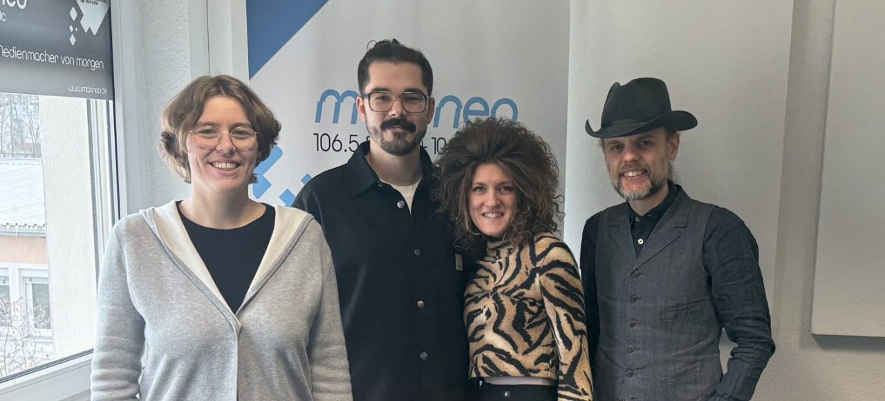 Das Foto zeigt die Moderatorin Lena Schnelle gemeinsam mit der Band Muddy What?.
