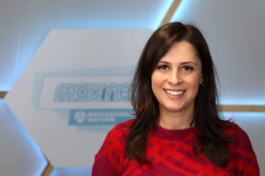 Das Foto zeigt Sahra Unan im Porträt vor dem max neo Logo.