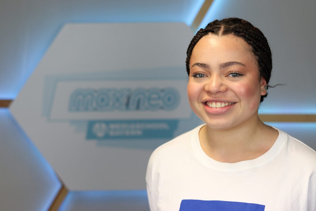 Das Foto zeigt Viktoriia Ozurumba vor dem max neo Banner.