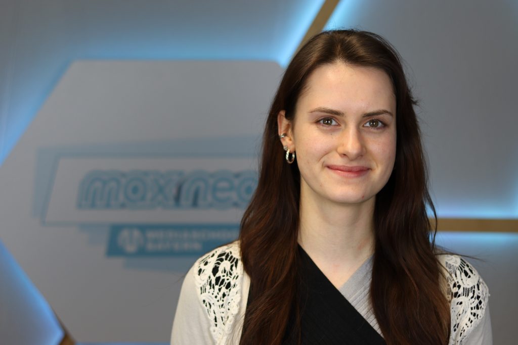 Das Foto zeigt Penelope Wissel im Porträt vor dem max neo Logo.