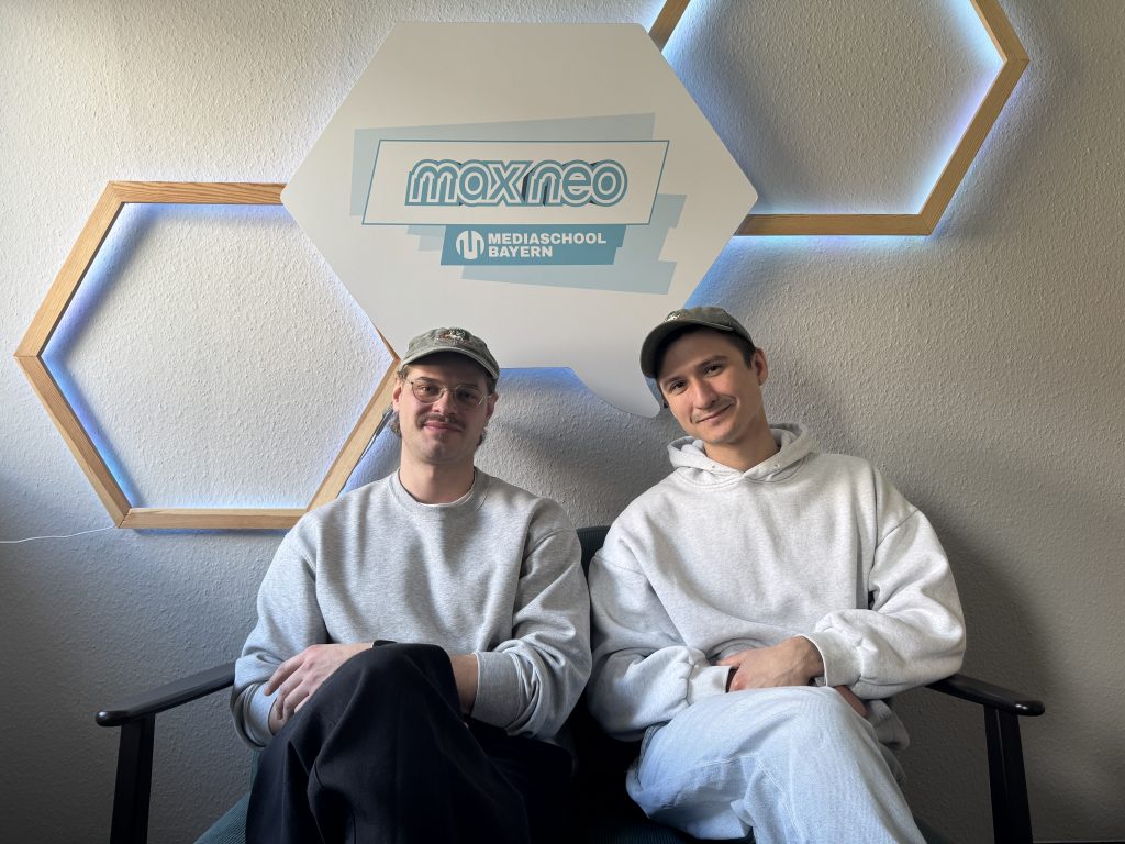 Auf einem Sofa sitzt links Bassist Philipp und auf der rechten Seite sitzt Julian.