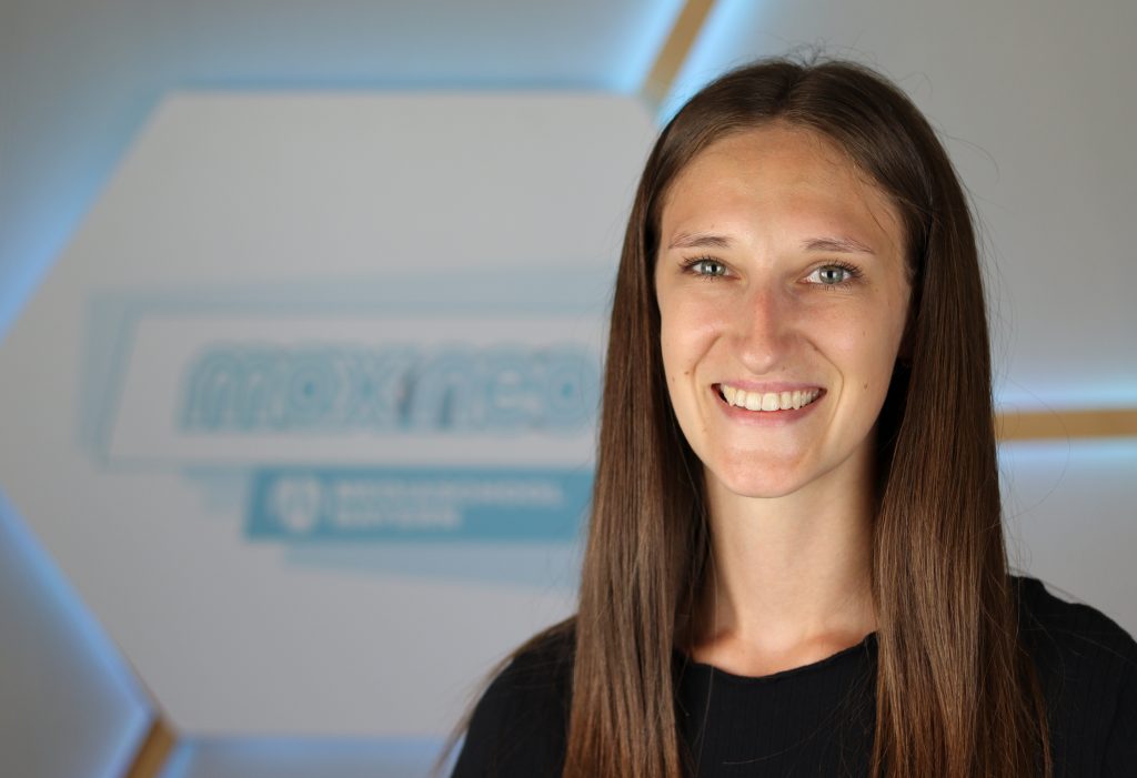Das Foto zeigt Emily Kehrer im Porträt vor dem max neo Logo.