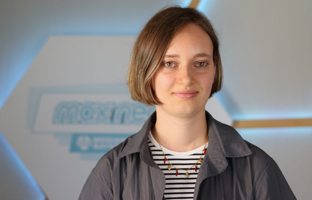 Das Foto zeigt Felizitas Hopf im Porträt vor dem max neo Logo.