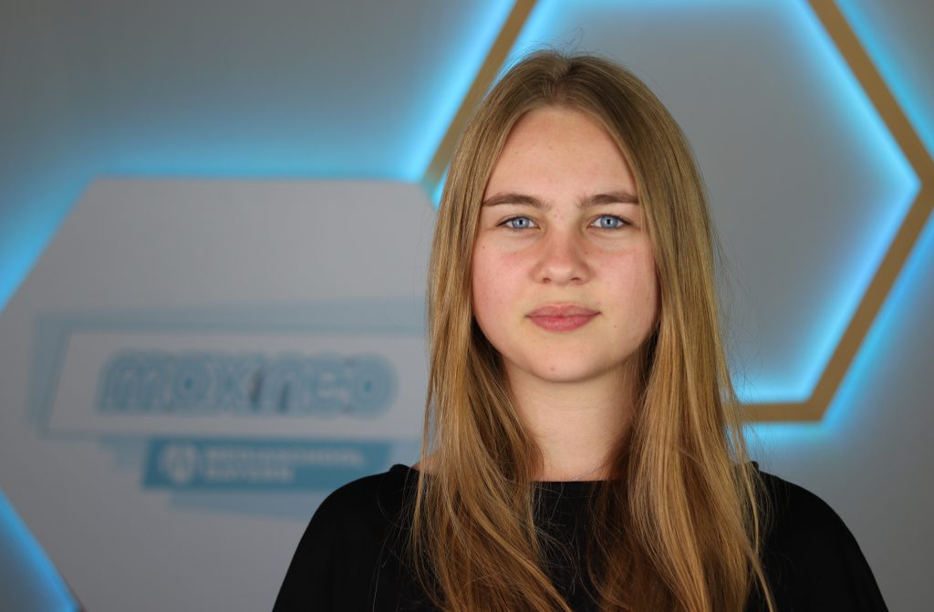Das Foto zeigt die max neo-Praktikantin Barbara Johne vor dem max neo Logo.
