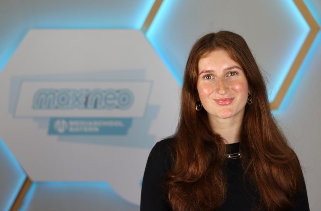 Das Foto zeigt Paula Hofmann im Porträt vor dem max neo Banner.